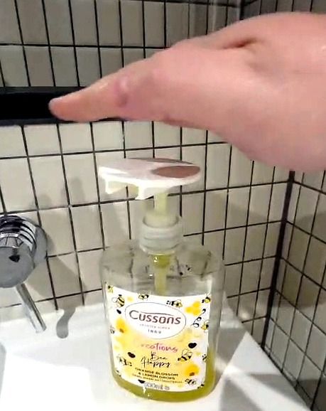 The flat outer edge of a hand, little-finger side, coming down onto the disc on a soap pump
