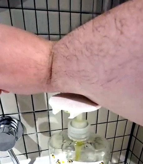 A forearm pressing the disc on a soap pump